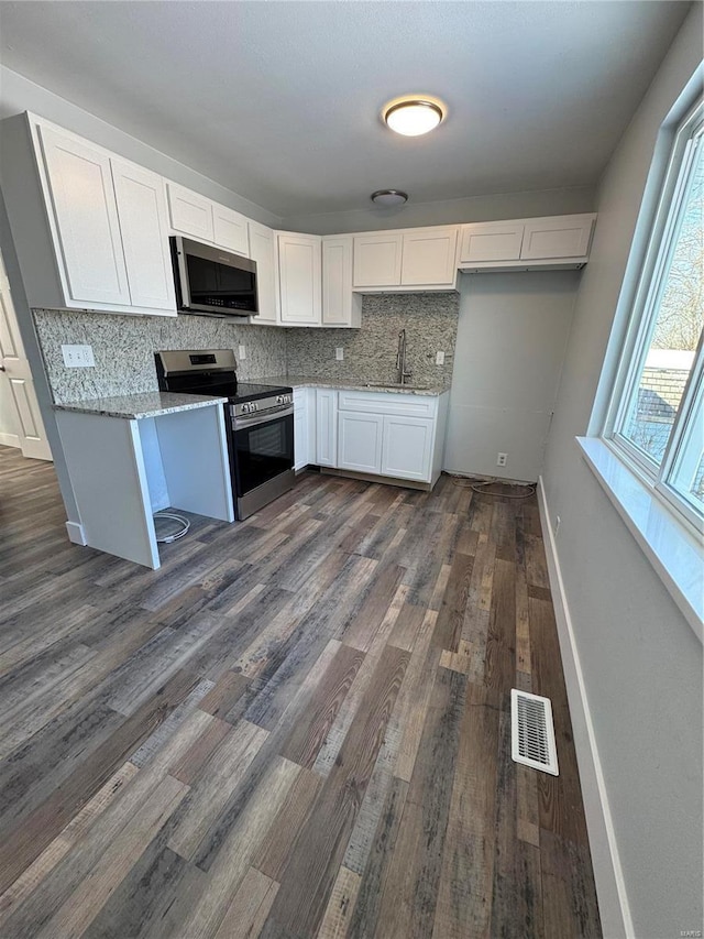 kitchen featuring white cabinetry, sink, light stone counters, dark hardwood / wood-style flooring, and appliances with stainless steel finishes