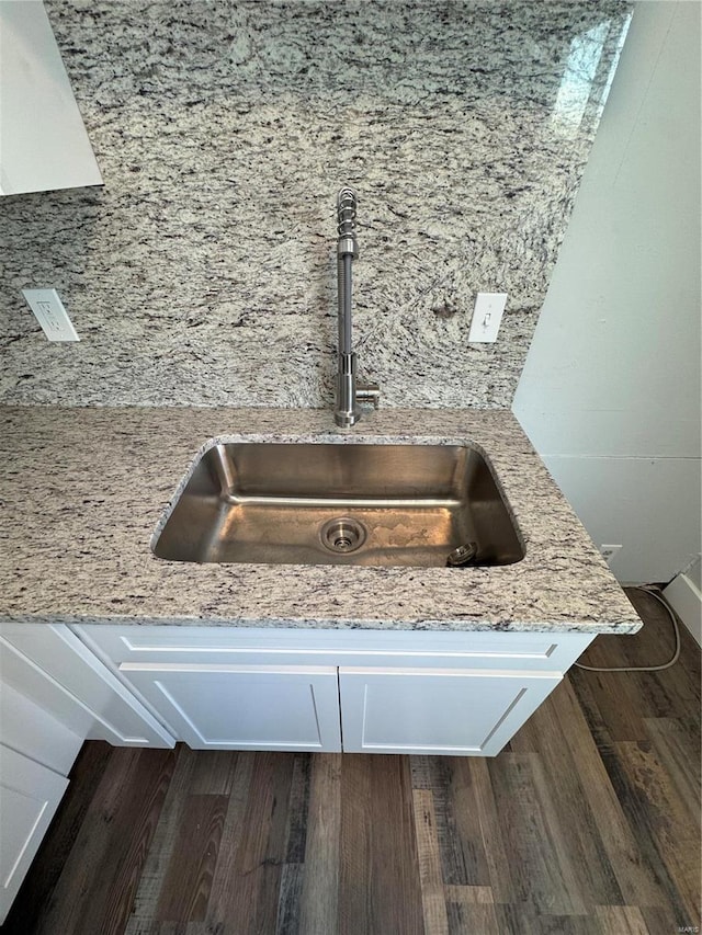 room details with light stone countertops, dark hardwood / wood-style flooring, tasteful backsplash, sink, and white cabinetry