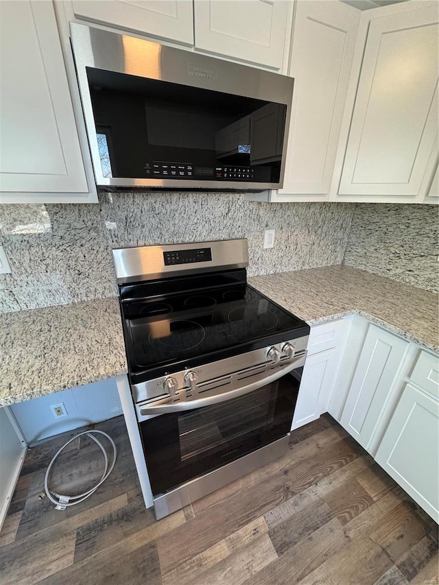 kitchen featuring light stone countertops, appliances with stainless steel finishes, backsplash, dark hardwood / wood-style floors, and white cabinetry