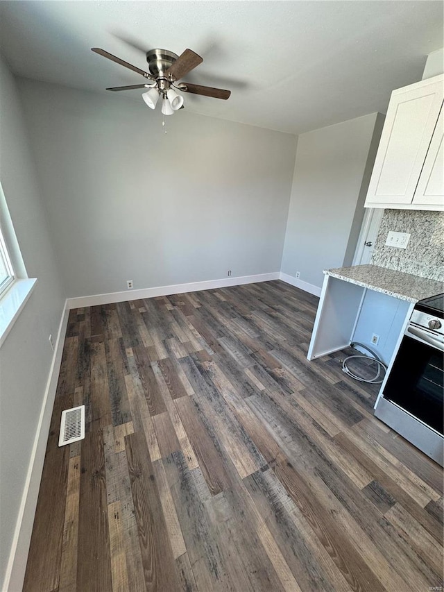 kitchen featuring light stone countertops, tasteful backsplash, dark hardwood / wood-style flooring, stainless steel range oven, and white cabinets