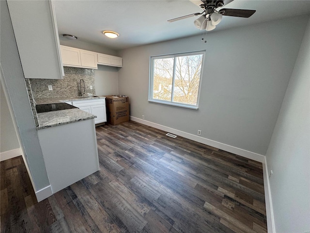 kitchen with white cabinets, sink, decorative backsplash, dark hardwood / wood-style floors, and light stone counters