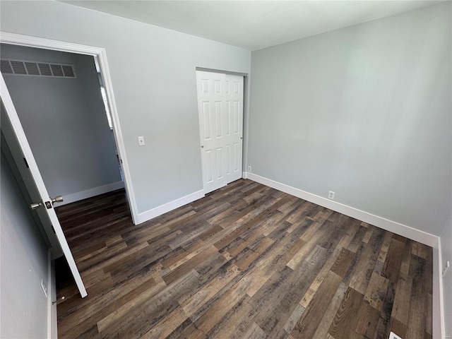 unfurnished bedroom with dark hardwood / wood-style flooring and a closet