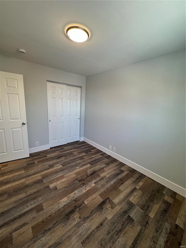 unfurnished bedroom featuring dark hardwood / wood-style flooring and a closet