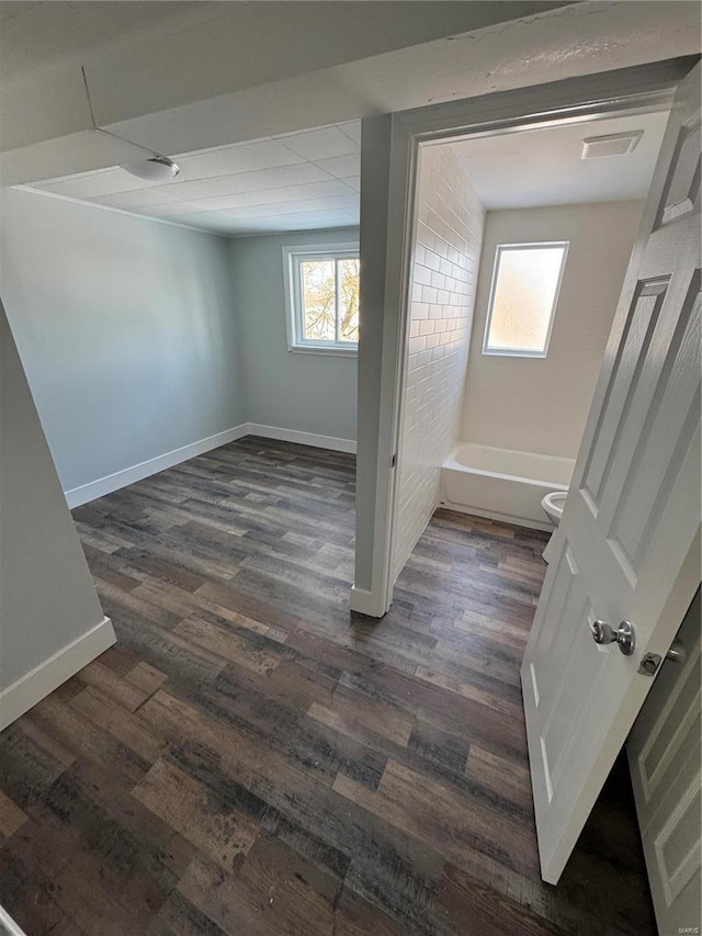 basement featuring dark hardwood / wood-style floors and brick wall