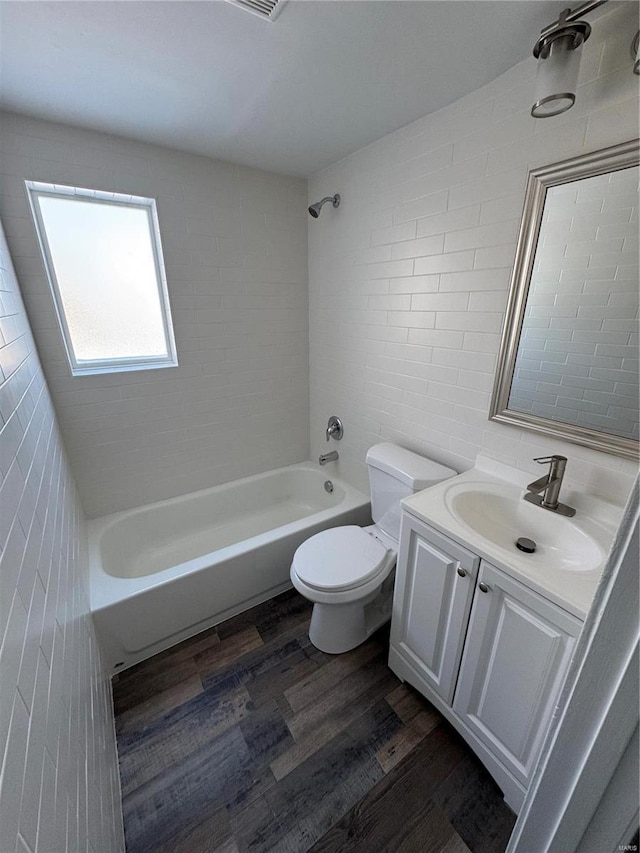 full bathroom featuring shower / bath combination, vanity, hardwood / wood-style flooring, tile walls, and toilet