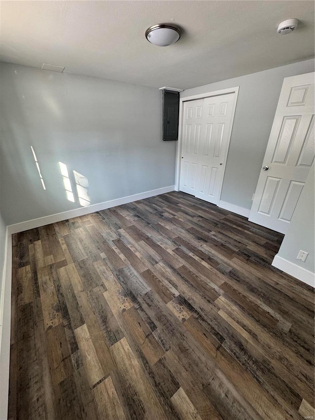 unfurnished bedroom featuring electric panel, a closet, and dark hardwood / wood-style floors