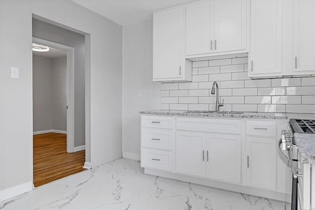 kitchen featuring backsplash, white cabinetry, and stainless steel range oven