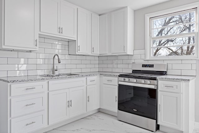 kitchen with decorative backsplash, sink, white cabinetry, and stainless steel range oven