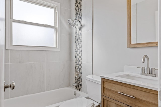 full bathroom with tiled shower / bath, vanity, and toilet