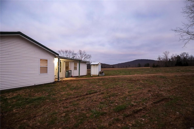 yard at dusk featuring a mountain view and a shed