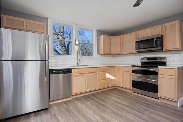 kitchen with sink, light brown cabinetry, hardwood / wood-style floors, and appliances with stainless steel finishes