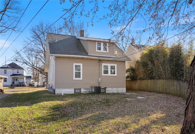 rear view of property featuring a lawn and cooling unit