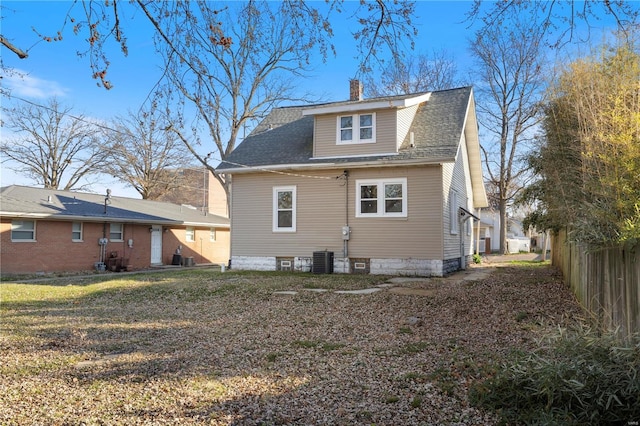 rear view of property with central air condition unit and a yard