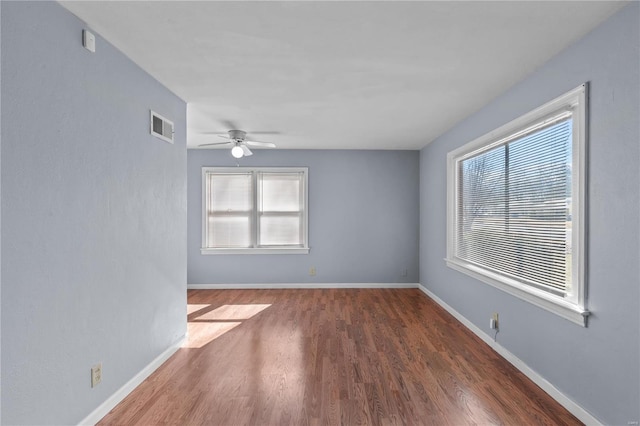 empty room with dark hardwood / wood-style floors, a wealth of natural light, and ceiling fan