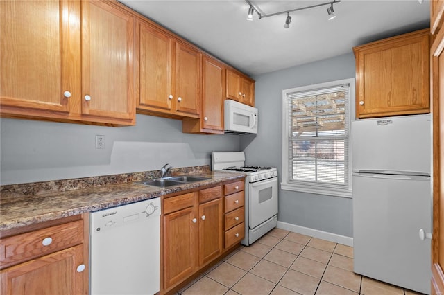 kitchen with rail lighting, dark stone counters, white appliances, sink, and light tile patterned floors