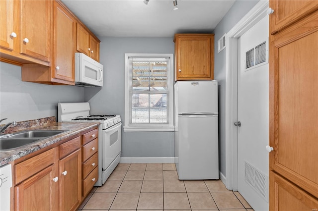 kitchen featuring sink, light tile patterned floors, and white appliances