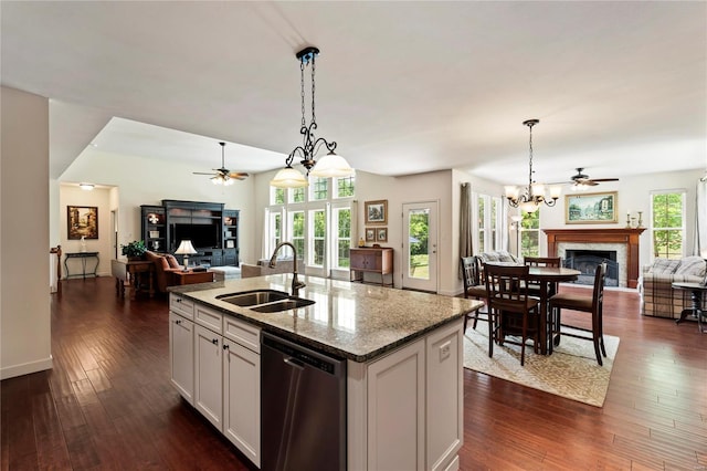 kitchen featuring open floor plan, stainless steel dishwasher, a fireplace, and a sink