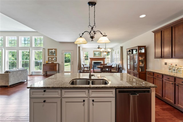 kitchen with a fireplace, open floor plan, a sink, an island with sink, and dishwasher