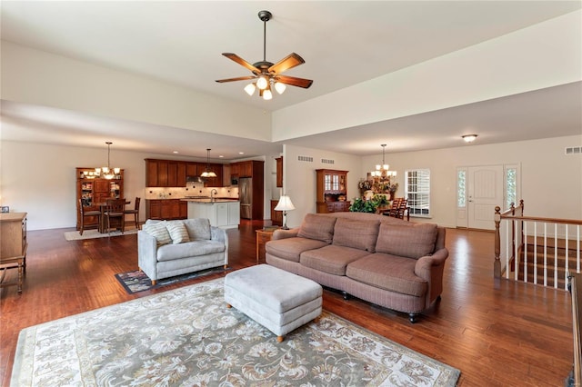 living area with ceiling fan with notable chandelier, dark wood-type flooring, visible vents, and recessed lighting