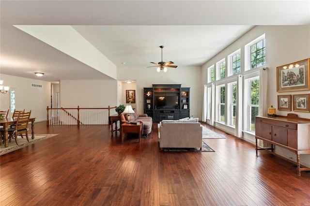 living area featuring ceiling fan with notable chandelier, dark wood-type flooring, and visible vents