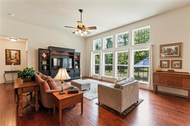 living area with a towering ceiling, wood-type flooring, visible vents, and a ceiling fan