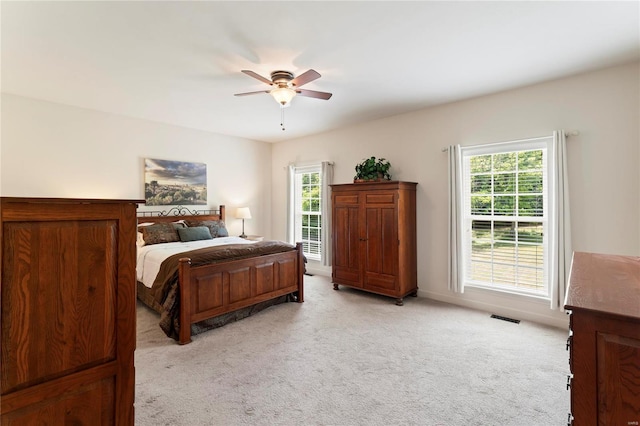 bedroom with a ceiling fan, light carpet, visible vents, and multiple windows