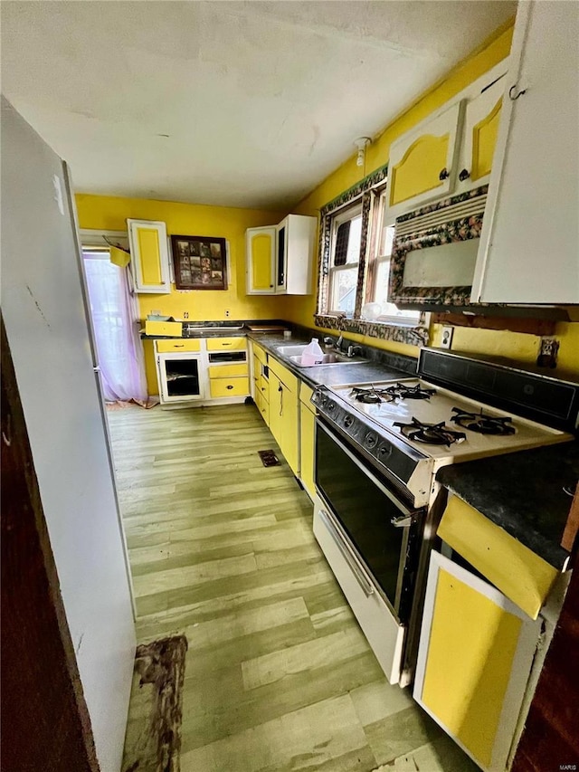 kitchen with white range with gas cooktop, white cabinetry, and sink