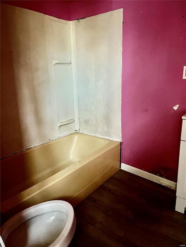 bathroom featuring hardwood / wood-style floors, a washtub, and toilet