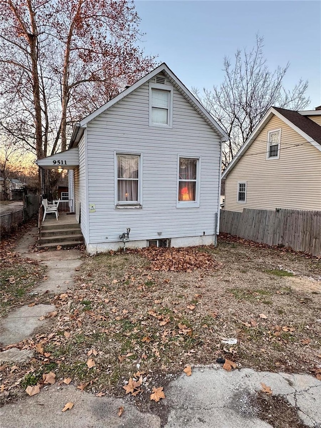 back house at dusk featuring covered porch