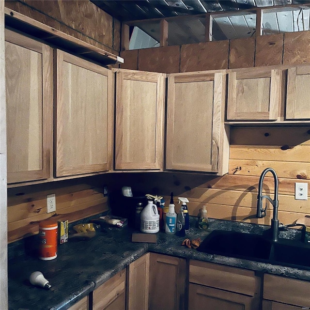 kitchen with wood walls, dark stone countertops, and sink