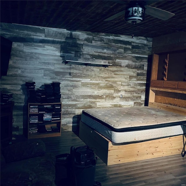 bedroom with dark hardwood / wood-style flooring and wooden walls