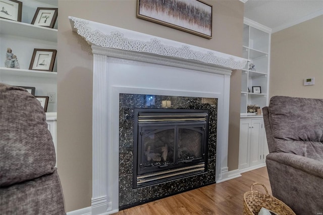 interior details featuring crown molding, wood-type flooring, built in features, and a fireplace