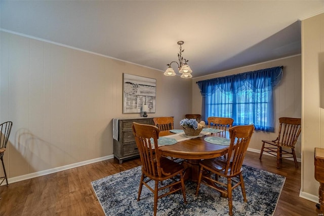 dining space with a notable chandelier, ornamental molding, and dark wood-type flooring