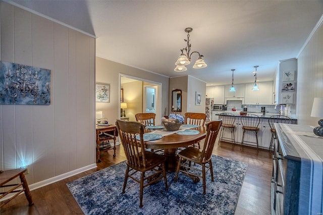 dining room with dark hardwood / wood-style floors, ornamental molding, and a notable chandelier