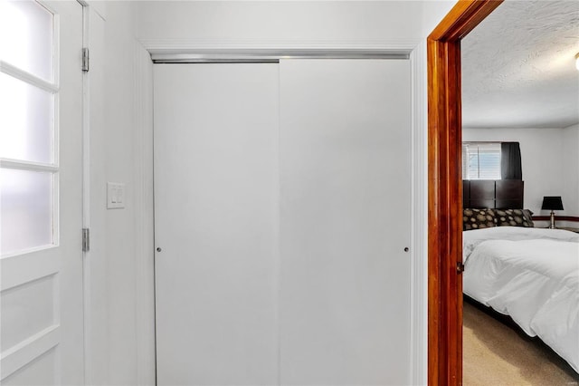 carpeted bedroom featuring a textured ceiling and a closet