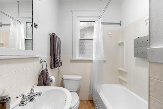 full bathroom featuring tile patterned floors, shower / bath combination with curtain, sink, toilet, and tile walls