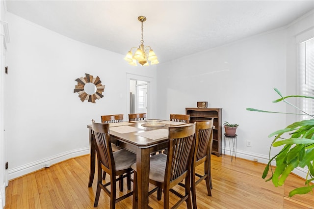 dining space with light hardwood / wood-style flooring and a notable chandelier