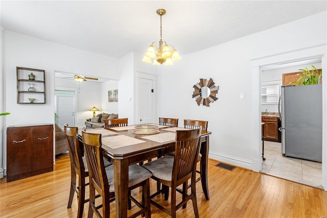 dining area with light wood-type flooring and ceiling fan with notable chandelier