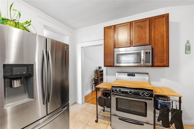 kitchen featuring light tile patterned floors, ornamental molding, and appliances with stainless steel finishes