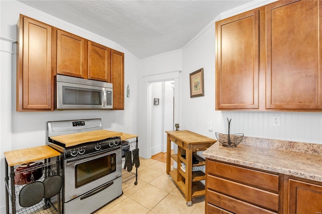 kitchen featuring a textured ceiling, lofted ceiling, light tile patterned floors, and stainless steel appliances