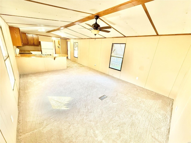 unfurnished living room with vaulted ceiling with beams, light carpet, and ceiling fan