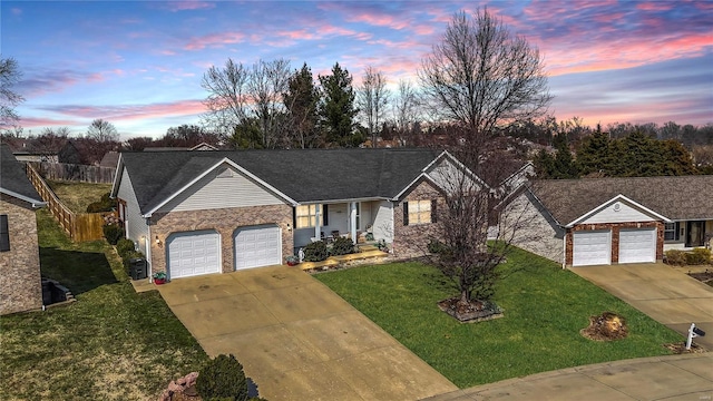 single story home featuring driveway, fence, a front yard, a garage, and brick siding