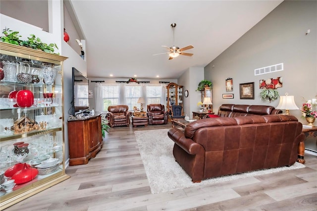 living room with light wood-style flooring, visible vents, high vaulted ceiling, and ceiling fan