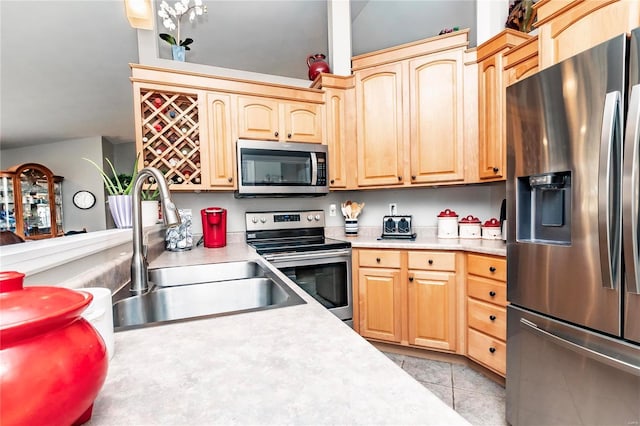 kitchen featuring light tile patterned floors, light brown cabinets, a sink, stainless steel appliances, and light countertops