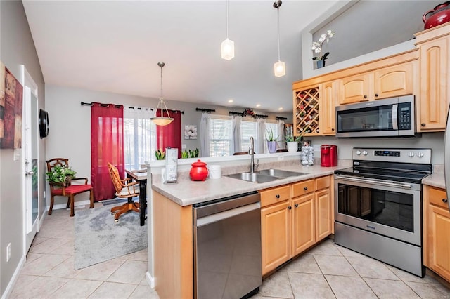 kitchen with light brown cabinetry, a sink, stainless steel appliances, a peninsula, and light tile patterned flooring