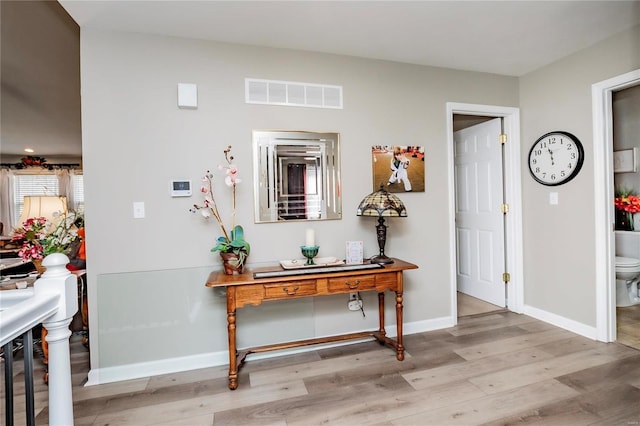 hallway featuring visible vents, baseboards, and light wood-style floors