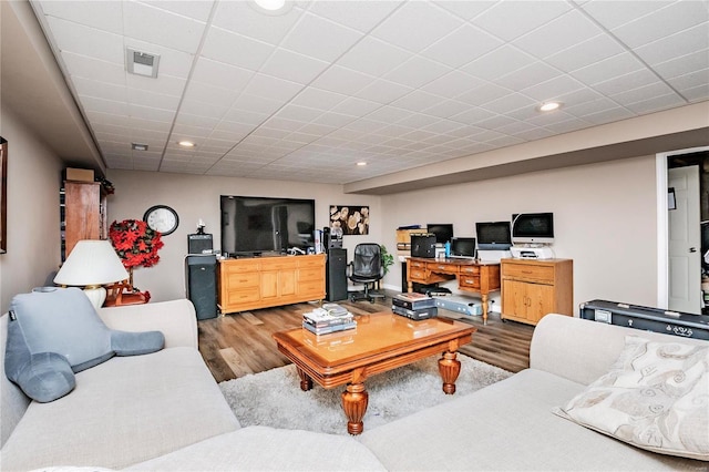 living area with recessed lighting, wood finished floors, visible vents, and a drop ceiling