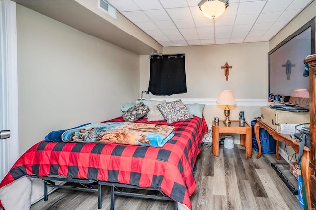 bedroom featuring a drop ceiling, visible vents, and wood finished floors