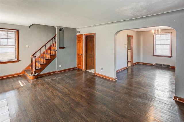 unfurnished room featuring wood-type flooring, visible vents, stairway, and baseboards