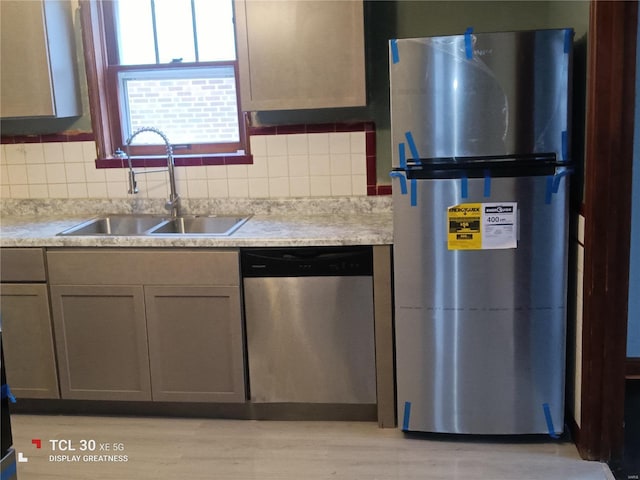 kitchen featuring stainless steel appliances, tasteful backsplash, a sink, and light countertops